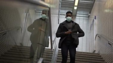 Black man wearing covid mask descending metro subway stairs