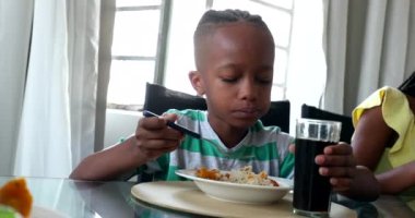Child eating lunch. Black African mixed race kid eats meal with family