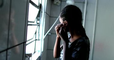 Black mixed race teen girl putting earrings