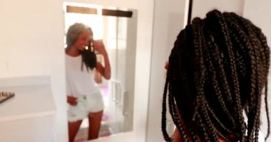 Teenage adolescent girl taking selfie photo in front of mirror reflection. Black African ethnicity