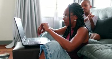 Black mother working from home in front of laptop computer