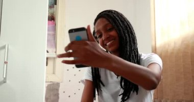 Siyah kız telefonuyla selfie çekiyor. Karışık ırk ergen kız kendi fotoğrafını çekiyor.