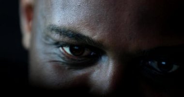 Close-up black man face and eyes looking at laptop computer screen at night