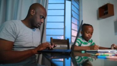 Black parent working from home with child son doing homework