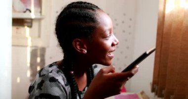 Teen girl listening to audio message on smartphone device. African black ethnicity