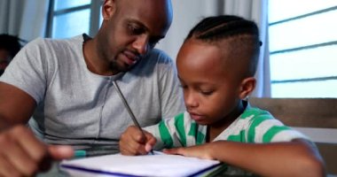 Baba, oğluna ev ödevinde yardım ediyor. Afrikalı siyahi baba küçük çocuğa akıl hocalığı yapıyor