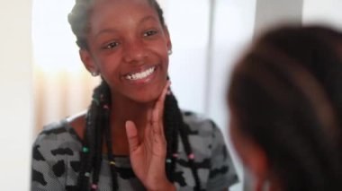 Black African teen girl smiling in front of mirror