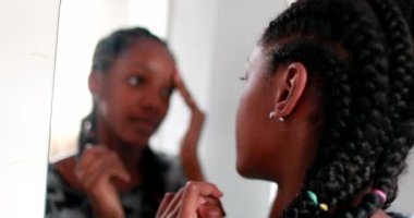 Kendine güvenen genç kız aynada kendine bakıyor.