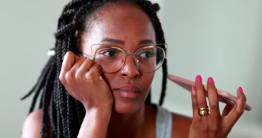 Black woman listening to voice message on cellphone, African person sending voice message on smartphone