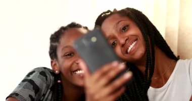 Two teenage black girls taking selfie with smartphone