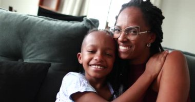 Anne ve çocuk kameraya poz veriyor, siyah anne oğlunu öpüyor.