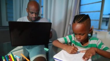 Father and child at home, dad in front of computer, son drawing next to parent