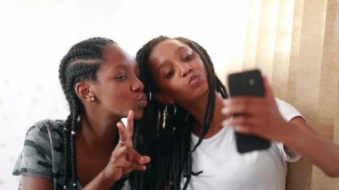 African teenage girls taking selfie with cellphone. Black mixed race girlfriends taking picture of themselves with smartphone