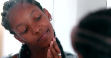 Genç kız aynanın önünde sivilce temizliyor. Siyah Afrika etnik kökeni