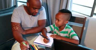 Baba, oğluna ev ödevinde yardım ediyor. Afrikalı siyahi baba küçük çocuğa akıl hocalığı yapıyor