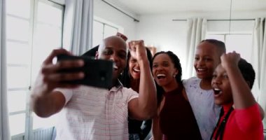 Afrikalı aile cep telefonuna bakarak başarıyı alkışlıyor