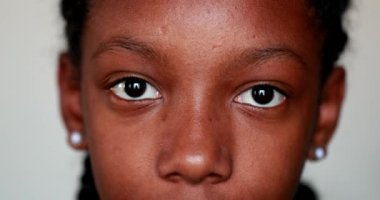 Genç siyah kız kameraya bakıyor.