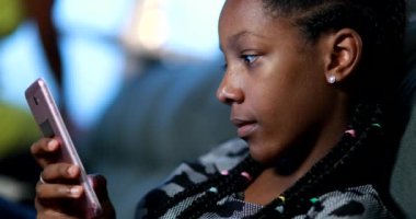 African teen girl reading content on cellphone device reacting with shock emotion