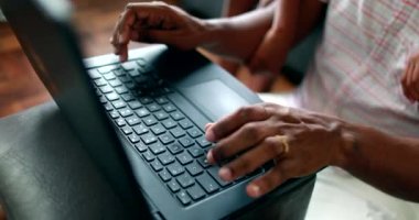 Oğlu izlerken, Afrikalı baba evde dizüstü bilgisayarla çalışıyor.