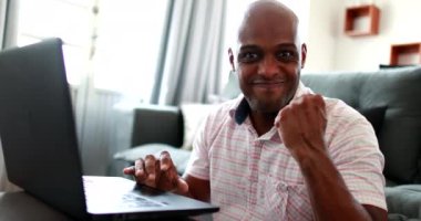 Confident black man cheering success looking at camera raising fist. African person celebrating notification