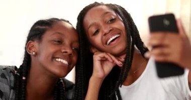 African girls taking selfie with cellphone, girlfriends posing taking photo of themselves. Rack focus