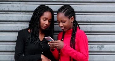 Teen black girls using cellphone, adolescent girlfriends laughing and smiling on social media