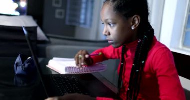 Gizli zenci kız geceleri dizüstü bilgisayarın önünde ders çalışıyor.