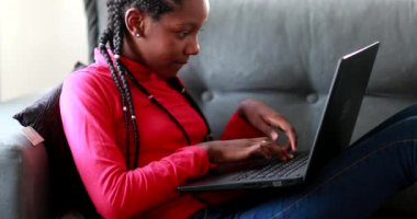 Evdeki kanepede dizüstü bilgisayar kullanan kız.