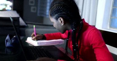 Akşamları ödev yapan Afrikalı genç bir kız, bilgisayarın önünde not yazan siyah ergen bir kadın.