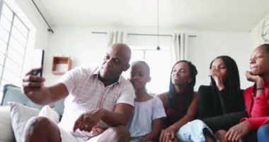 Baba elinde cep telefonu, çocuklarıyla ve eşiyle selfie çekiyor.