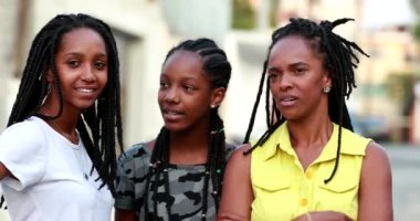 Anne ve genç kızları birlikte dedikodu yapıyorlar. Afrikalı anne ve ergen kızlar dışarıda konuşuyorlar.