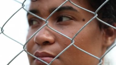 Pensive black woman behind metal fence
