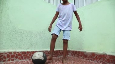 Young boy playing soccer by himself. Black African mixed race kid plays with ball