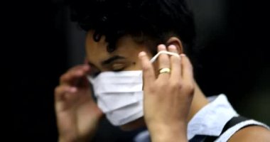 Mixed race woman putting face mask while riding subway. African Amercian girl wearing covid-19 mask