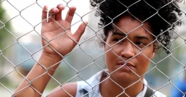 Metal çit tutan dalgın, üzgün siyah kadın