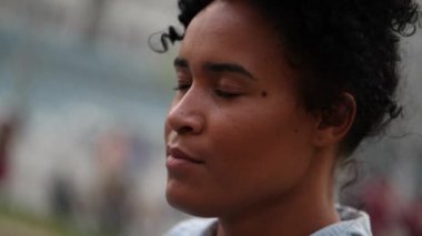 Mixed race woman taking a deep breath outside