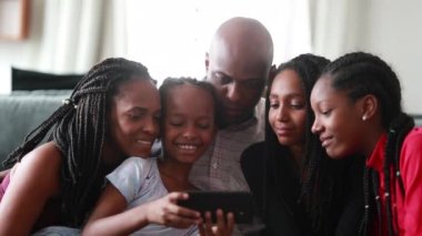 African family using cellphone together communicating with family member at distance
