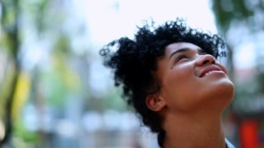 Mixed race young black African woman looking up to the sky smiling