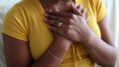 Grateful hopeful black woman holding hands on chest feeling thankful