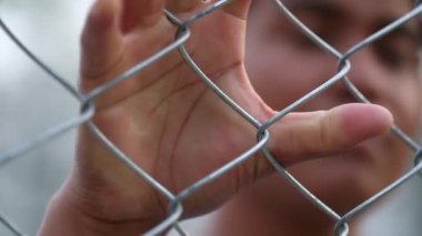 Mixed race woman metal bars holding into security gate