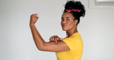 Young black woman showing muscle smiling. Afro american girl shows strength