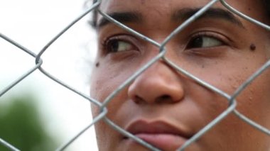 Mixed race woman behind fence. Thoughtful pensive African person