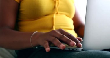 Genç melez kadın dizüstü bilgisayar kullanıyor.