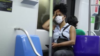 Black woman commuting during pandemic wearing face mask inside subway metro