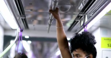 Metro tırabzanı tutan bir kadın. Kovid-19 yüz maskesi takıyor.