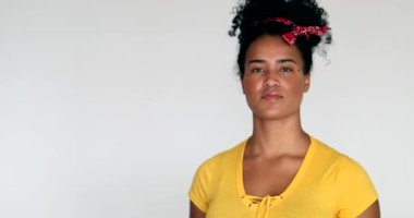 Beyaz arka planda duran, sarı elbiseli genç siyahi kadın.