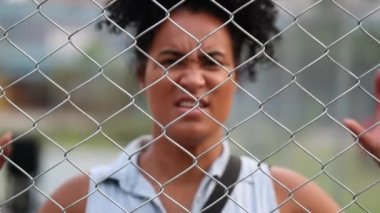 Angry black woman behind fence screaming