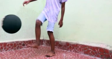 Afrikalı çocuk topla oynuyor, siyah çocuk tek başına spor yapıyor.