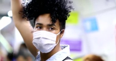 Woman standing at subway holding handrail wearing covid-19 face mask