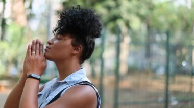 Young black African american woman praying outside